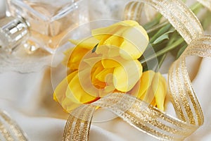 Yellow tulips, perfume and gold ribbon