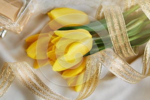 Yellow tulips, perfume and gold ribbon