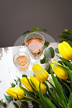 Yellow tulips on a white table with a glass of rose wine, close-up
