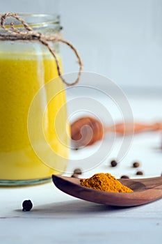 Yellow turmeric spice on a wooden spoon. Close-up. The ingredient for a healthy drink is golden milk