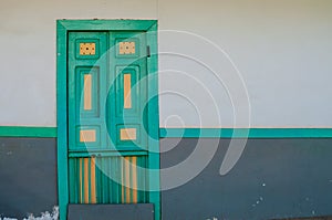 Yellow turquoise green wooden door of a colonial