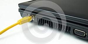 Yellow twisted pair ethernet network cable connected to laptop