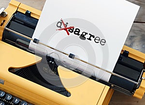 A yellow typewriter has the word agree disagree crossed out