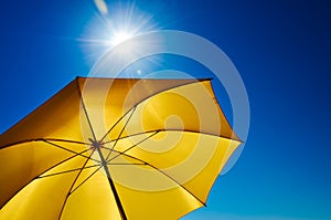Yellow Umbrella with Bright Sun and Blue Sky