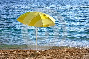 Yellow umbrella on summer beach. Sea beach with sun umbrella waiting for tourists. Happy summer vacations concept