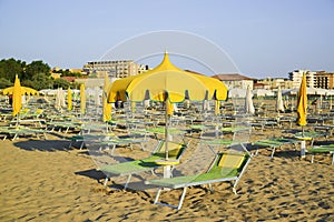 Yellow umbrellas and chaise lounges on the beach of Rimini in Italy