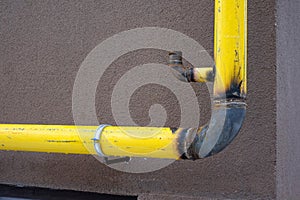 Yellow unfinished gas pipe on building wall. The concept of gasification of houses