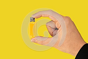 Yellow USB pen drive on hand with isolated yellow background