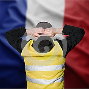 Yellow vests protests in France. A young man stands with his back and holds his hands on his head as a sign of obedience.