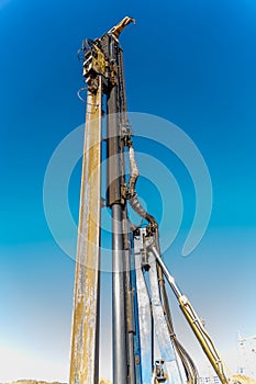 The yellow vibrating piling machine removes Larssen sheet piling from the ground photo