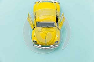 Yellow vintage retro toy car isolated on blue pastel colorful background