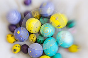 Yellow, violet, blue and green Easter egge with had drawings of butterflies, polka dots, spirals