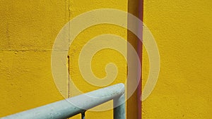 The yellow wall and the grey pipe.