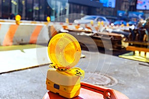 Yellow warning orange construction light mounted on a barricade intended to warn at construction site