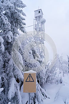 Yellow warning sign in front of a frozen watchtower