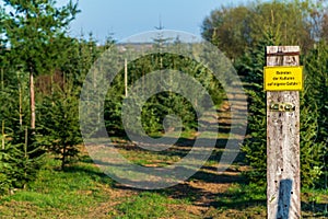 Yellow warning sign with German text `Entering the crops at your own risk` at a hiking path