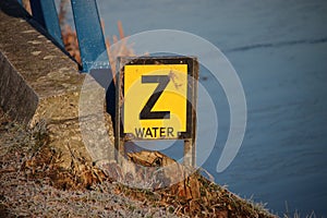 Yellow warning sign with letter `Z ` to warn that a water pipe have sunken on the bottom of the canal.
