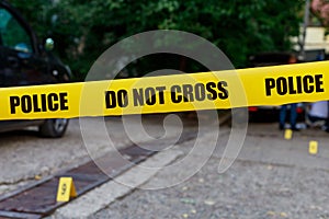 Yellow warning tape with the words POLICE DO NOT CROSS on the blurred background of the crime scene