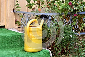 Yellow water bucket jug placed on stone steps in front of cottage door