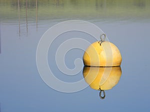 Yellow water buoy floating on calm lake