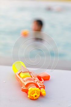 Yellow water gun by the swimming pool, summer holiday concept