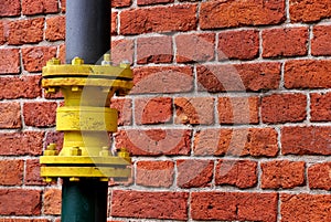 Yellow water pipe and red brick wall as city background.