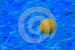 Yellow water polo ball on water background photo