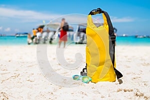 Yellow waterproof shoulder bag with sunglasses on beach sand at