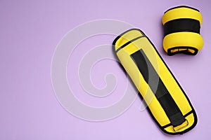 Yellow weighting agents on violet background, flat lay. Space for text