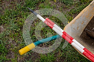 Yellow wheelbarrow and ranging poles in an archaeological excavation