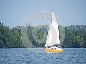 Yellow and white boat sailing on a lake on a sunny day