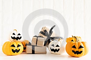 Yellow and white ghost pumpkin with gift box on white brick bloc