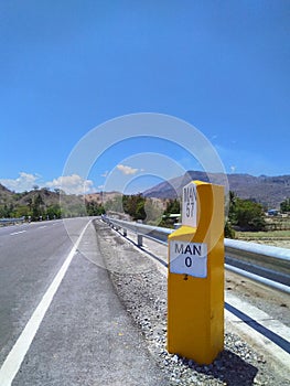 Yellow white kilometer sign with blue sky in Manatuto, Timor-Leste.. photo