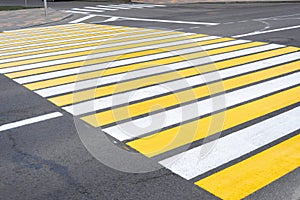 Yellow-white pedestrian crossing on asphalt. Close-up of the road