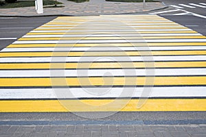 Yellow-white pedestrian crossing on asphalt. Close-up of the road