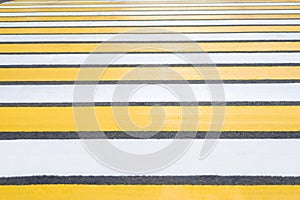 Yellow-white pedestrian crossing on asphalt. Close-up of the road.