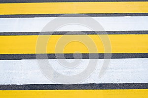 Yellow-white pedestrian crossing on asphalt. Close-up of the road