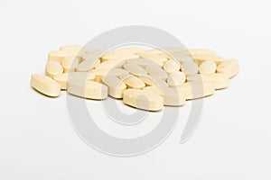 Yellow and white pills on the white background