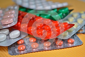 Yellow, white, red, green medical tablets in pack, tablets packed in blisters on yellow background