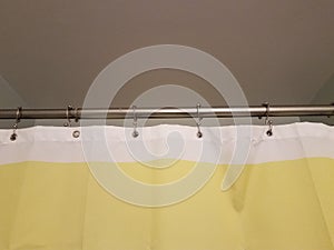 Yellow and white shower curtain with metal bar