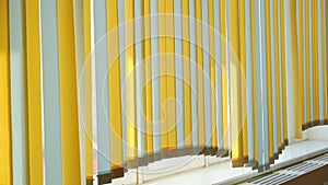 Yellow and white vertical paper sunblinds hangs in room over wooden sill