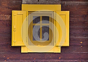 Yellow window on wooden wall