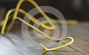 A yellow wire on a wooden background, the concept is the internet and the wooden age