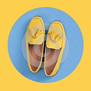 Yellow woman`s moccasins shoes in blue circle on yellow