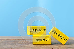 Yellow wooden blocks with text DREAM IT, BUILD IT and BELIEVE IT