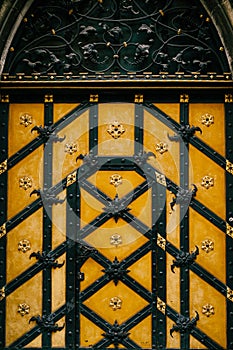 Yellow wooden door with wrought iron elements and floral decor