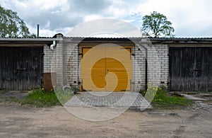 yellow wooden garage door between two unpainted