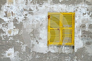 Yellow wooden window shutters on the old stone wall