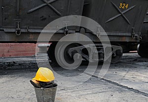 Yellow worker helmet and train wagons on a coal mine