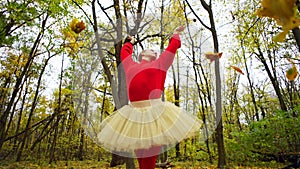 Yellowed leaves slowly circle around a woman who elegantly raises her hands.